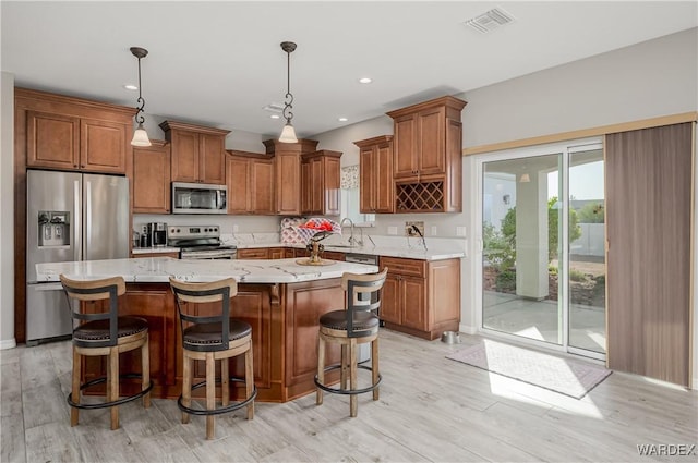 kitchen with visible vents, appliances with stainless steel finishes, brown cabinets, and a wealth of natural light