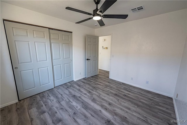 unfurnished bedroom with baseboards, a closet, visible vents, and wood finished floors