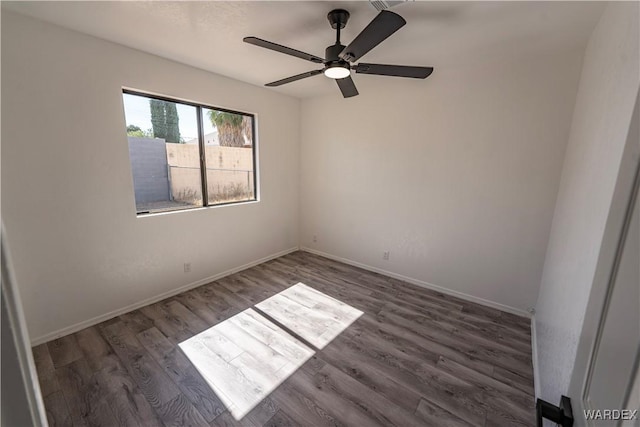 spare room featuring ceiling fan, dark wood finished floors, and baseboards