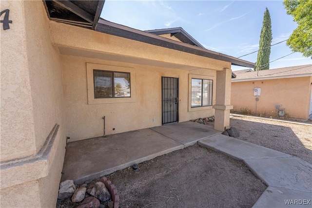 entrance to property with a patio and stucco siding