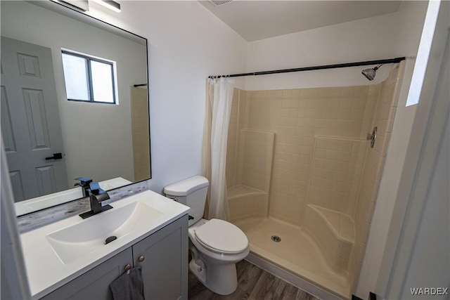 bathroom with visible vents, toilet, a shower stall, vanity, and wood finished floors