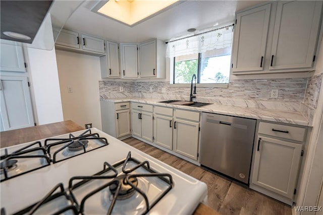 kitchen featuring white range with gas cooktop, tasteful backsplash, dishwasher, wood finished floors, and a sink