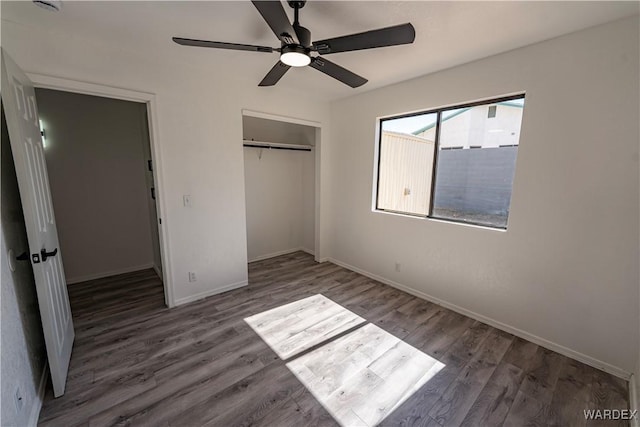 unfurnished bedroom featuring dark wood-style flooring, a closet, a ceiling fan, and baseboards