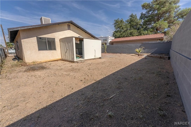 exterior space featuring an outdoor structure, a fenced backyard, and stucco siding