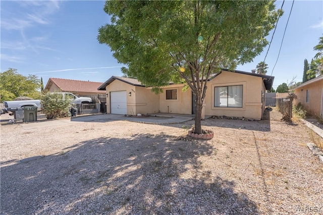 view of front of house with a garage, concrete driveway, fence, and stucco siding