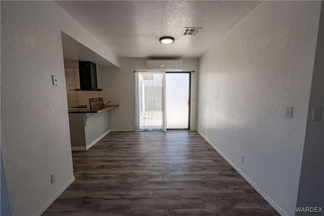 unfurnished dining area with a textured wall, an AC wall unit, and visible vents