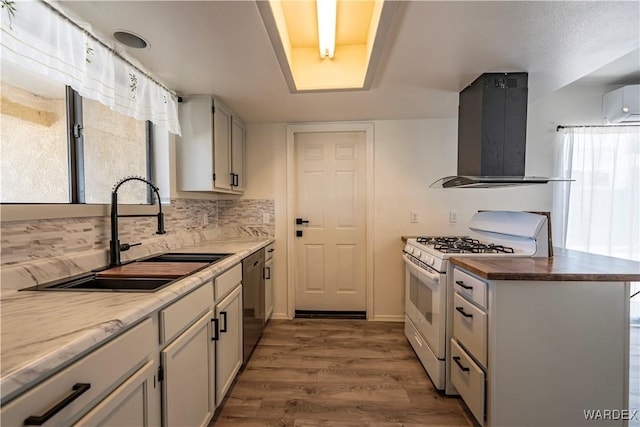 kitchen with tasteful backsplash, wood finished floors, island exhaust hood, white gas range, and a sink