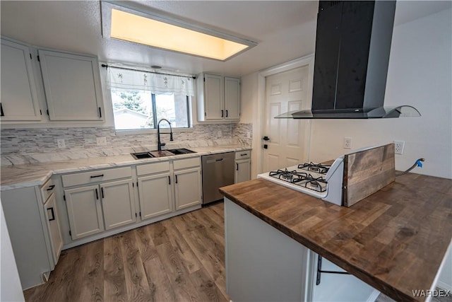 kitchen featuring a sink, wood counters, white cabinetry, wall chimney range hood, and dishwasher