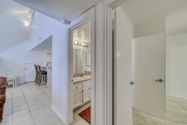 hallway featuring a sink and light tile patterned flooring