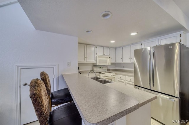 kitchen featuring recessed lighting, white cabinetry, a peninsula, and white appliances
