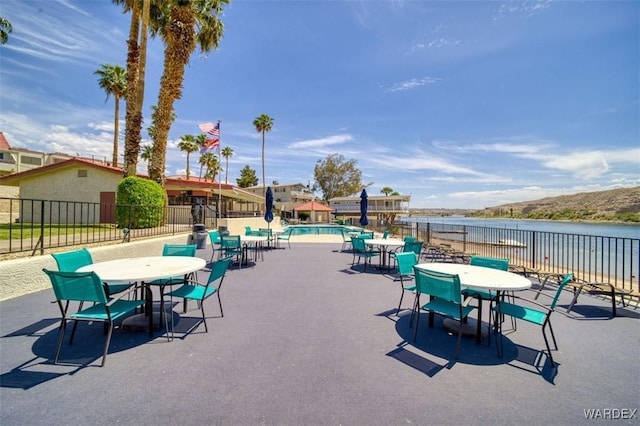 surrounding community featuring fence, outdoor dining space, a water view, a swimming pool, and a patio