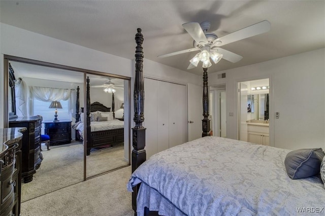 bedroom with carpet flooring, ceiling fan, two closets, ensuite bathroom, and visible vents