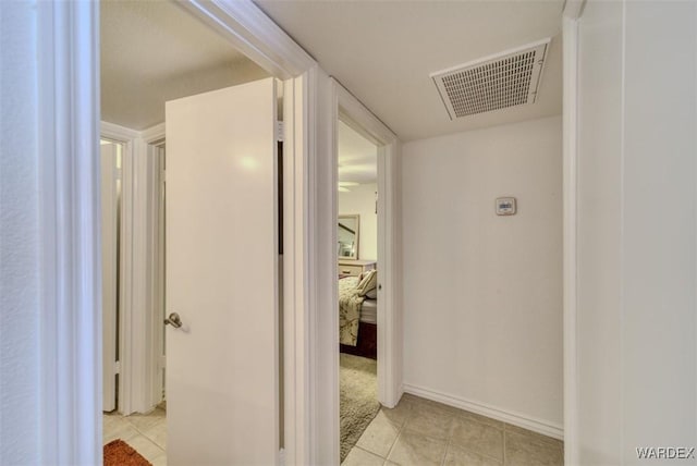corridor featuring baseboards, light tile patterned flooring, and visible vents