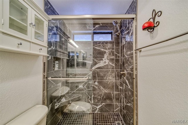 full bath with a textured wall, toilet, and a shower stall