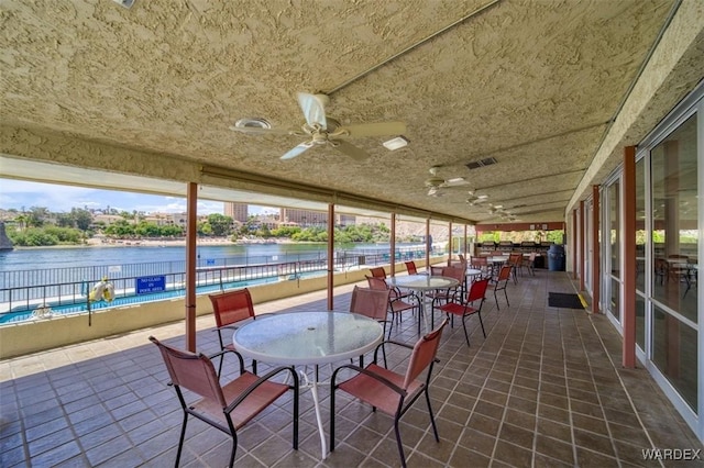 sunroom featuring plenty of natural light, a water view, and tile patterned flooring