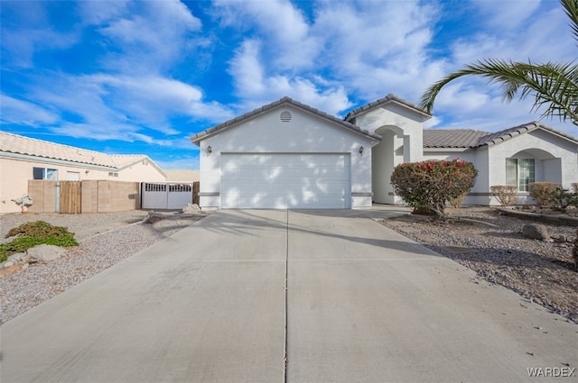 mediterranean / spanish-style home featuring an attached garage, fence, concrete driveway, a tiled roof, and stucco siding