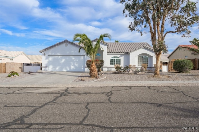 view of front of home with concrete driveway, a tile roof, fence, and stucco siding