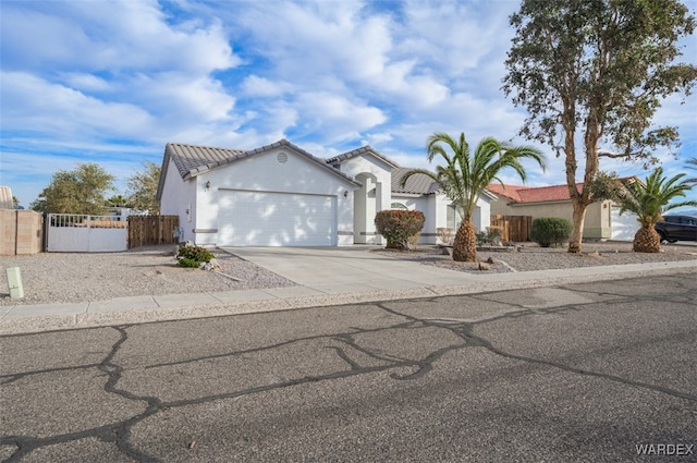 mediterranean / spanish-style house with driveway, a garage, a tiled roof, fence, and stucco siding