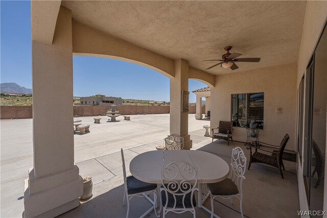 view of patio featuring ceiling fan, fence, a mountain view, and outdoor dining space