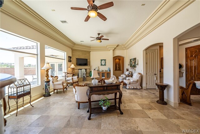 living room with arched walkways, a ceiling fan, baseboards, visible vents, and crown molding