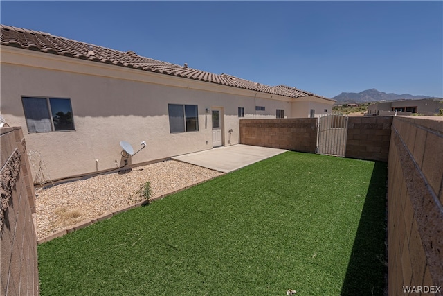 view of yard featuring a patio area, a fenced backyard, a gate, and a mountain view