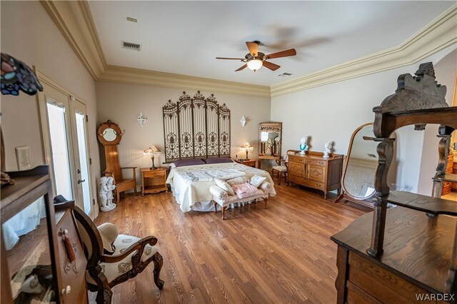 bedroom featuring light wood-style floors, visible vents, and ornamental molding