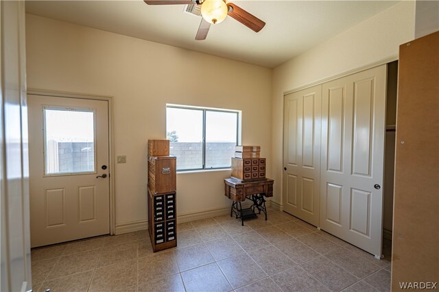 foyer entrance featuring light tile patterned floors, ceiling fan, and baseboards