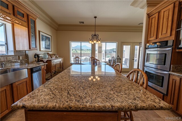 kitchen with a breakfast bar, pendant lighting, double oven, glass insert cabinets, and light stone countertops