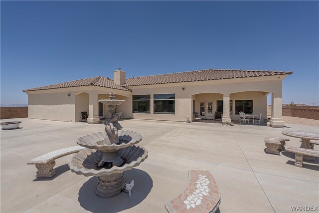 back of property with a patio, a chimney, stucco siding, fence, and a tiled roof