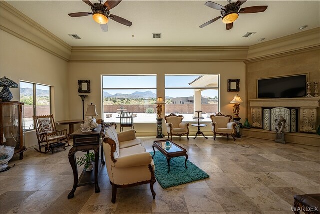 living room with a ceiling fan, visible vents, and crown molding