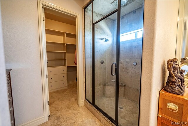 bathroom with a spacious closet and a stall shower