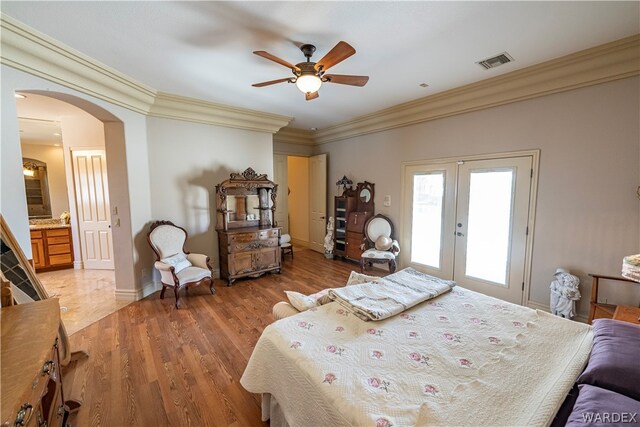 bedroom with visible vents, arched walkways, light wood-style flooring, ornamental molding, and french doors