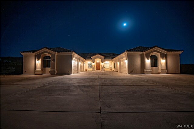 mediterranean / spanish-style house featuring a tiled roof, concrete driveway, and stucco siding