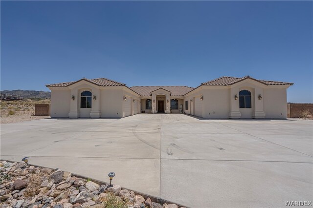 mediterranean / spanish-style house featuring stucco siding, entry steps, a garage, driveway, and a tiled roof