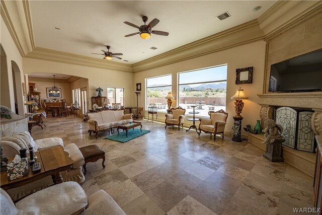 living area featuring a ceiling fan, arched walkways, visible vents, and a fireplace