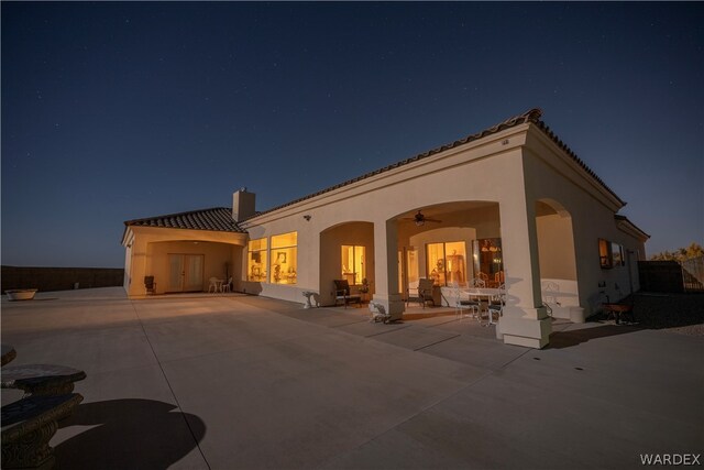 rear view of property featuring a patio area, ceiling fan, and stucco siding