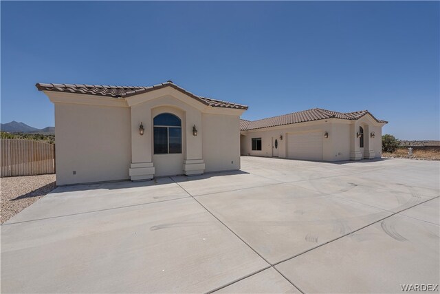 mediterranean / spanish home featuring a tiled roof, an attached garage, a mountain view, and stucco siding