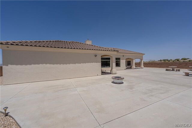 rear view of property with a patio, an outdoor fire pit, a tile roof, and stucco siding