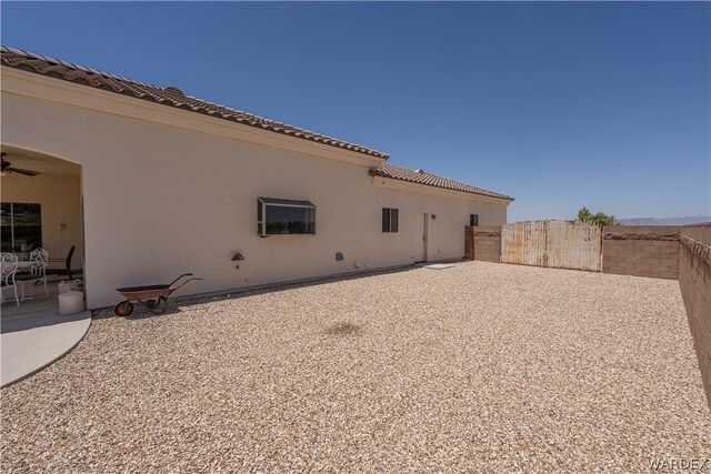 rear view of property featuring a patio, fence, a tiled roof, and stucco siding