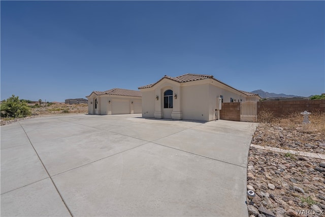 view of front facade with a tile roof, an attached garage, a gate, a mountain view, and driveway