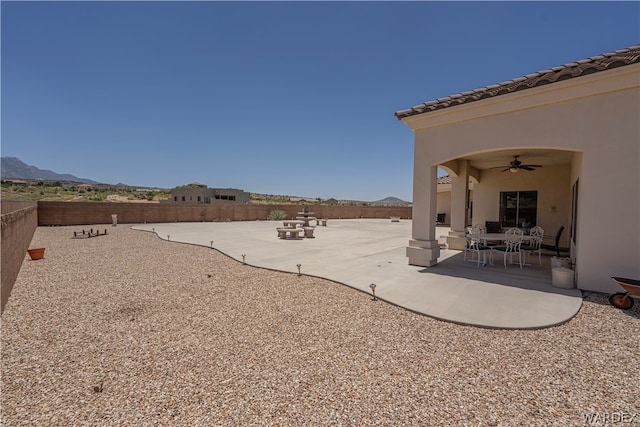 view of yard featuring a mountain view, a patio, a fenced backyard, and a ceiling fan