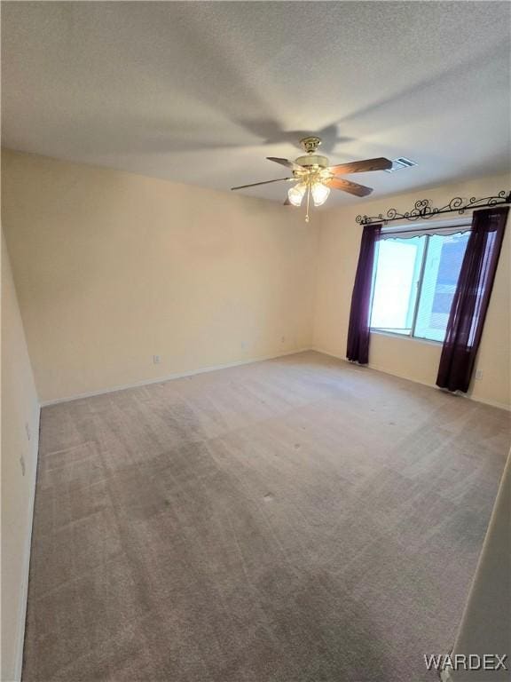 empty room featuring a textured ceiling, carpet, and a ceiling fan