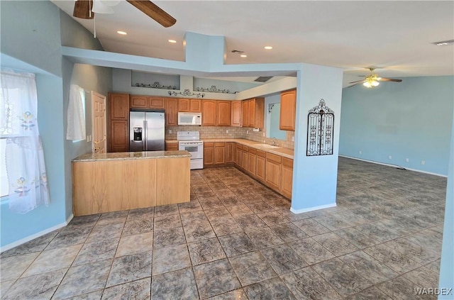 kitchen with white appliances, light countertops, a sink, and a peninsula