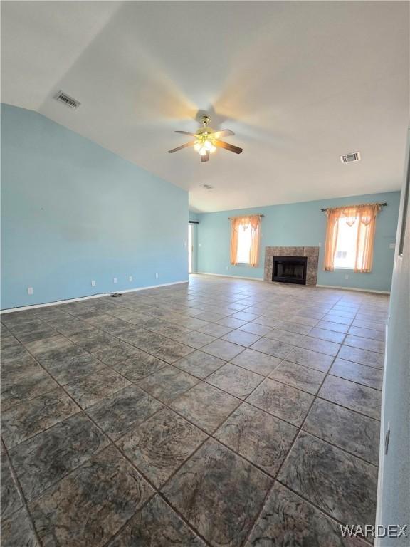 unfurnished living room with visible vents, vaulted ceiling, a high end fireplace, and a ceiling fan