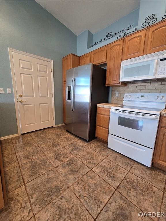 kitchen featuring baseboards, light countertops, white appliances, and decorative backsplash