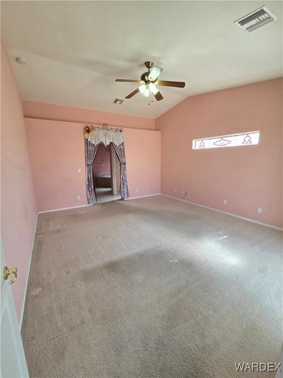 unfurnished living room with ceiling fan, carpet floors, visible vents, baseboards, and vaulted ceiling