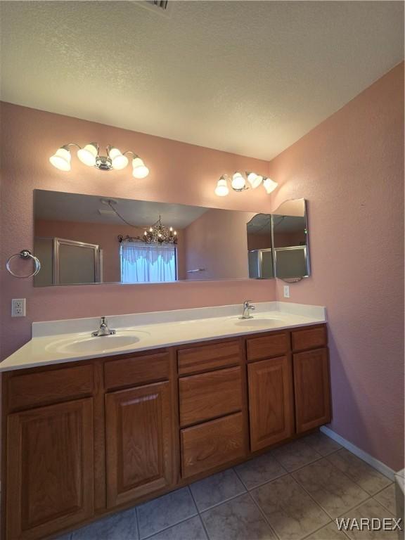 bathroom with tile patterned flooring, a sink, baseboards, and double vanity