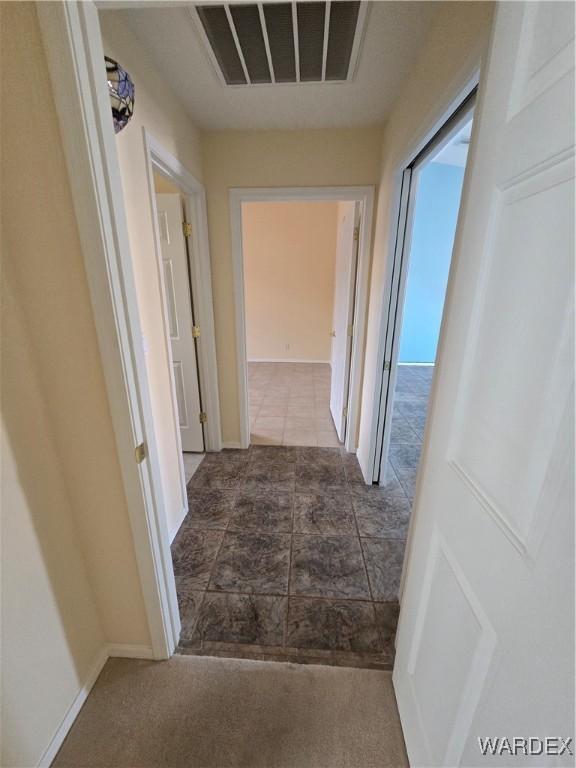 hall with carpet floors, visible vents, and baseboards