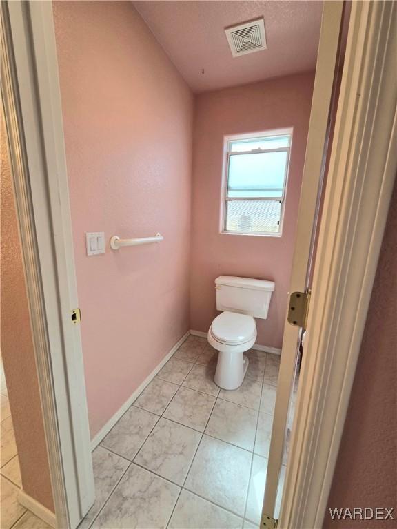 bathroom with toilet, baseboards, visible vents, and tile patterned floors