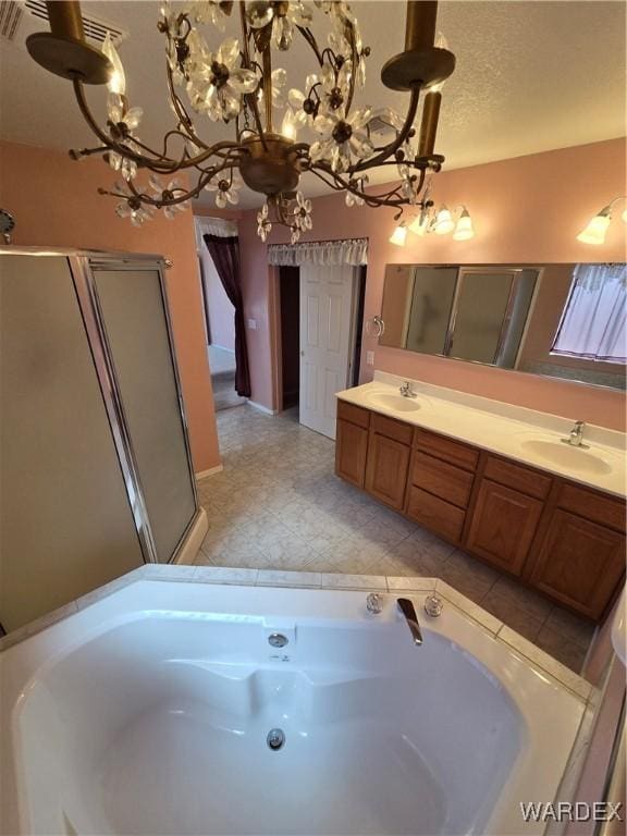 bathroom featuring a textured ceiling, double vanity, a sink, and a bath